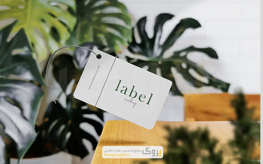 موکاپ مینیمال لیبل لباس شناور روی میز چوبی با گیاه